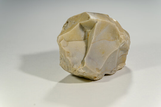 A round flint stone with a fracture on a white background.