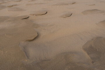 Wind-shaped beach sand featuring soft ridges and delicate contours formed by natural erosion.