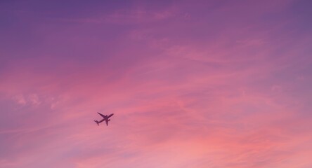 Fototapeta premium Commercial airplane descending through vibrant purple sky with pink clouds at sunset