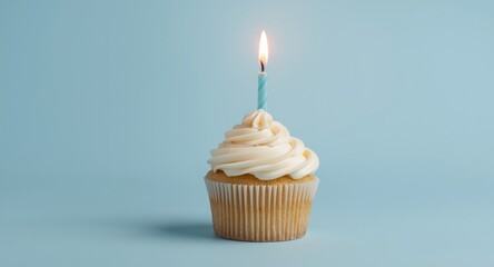 Obraz premium Cupcake with candlelight flickering on a pastel blue background symbolizing holiday and party greetings