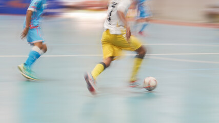 Naklejka premium Speed and action: Blurred legs of soccer players during an indoor match