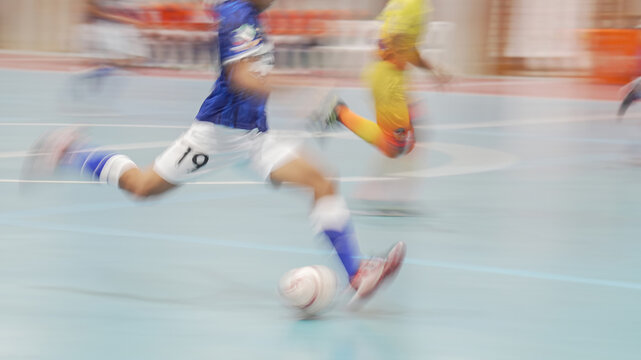 Action shot of a futsal player kicking the ball toward the goal with motion blur