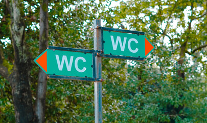 Directional signpost indicating restrooms in a park setting © Наталья Добровольска