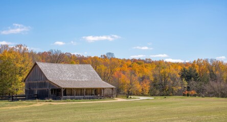 Obraz premium Rustic farmhouse set against a backdrop of colorful fall trees in calm countryside