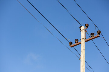 Electric power pole with wires and insulators against blue sky