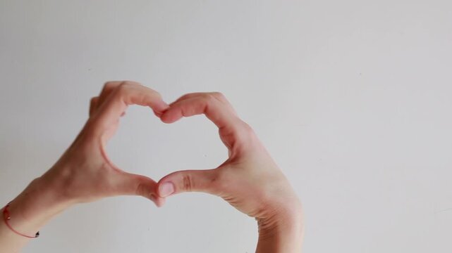 Female hands making heart shape gesture isolated on white background. Symbol of love, care, affection and romantic emotion.