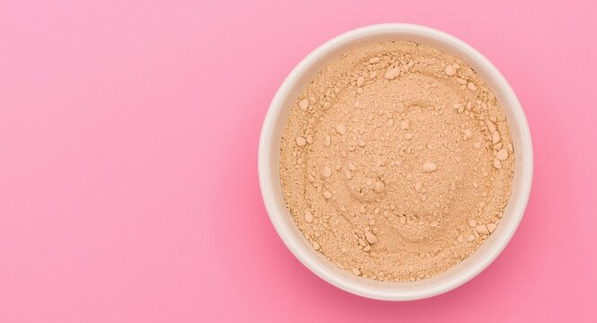 Ceramic bowl filled with colostrum skim milk powder on bright pink surface with empty area for text