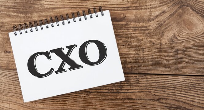 Business leadership focus shown by notebook containing CXO abbreviation on rustic wooden backdrop