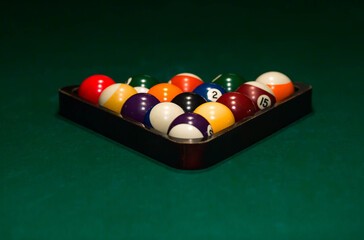 A billiard table with balls. A person sets the billiard balls on the billiard table to start the game.