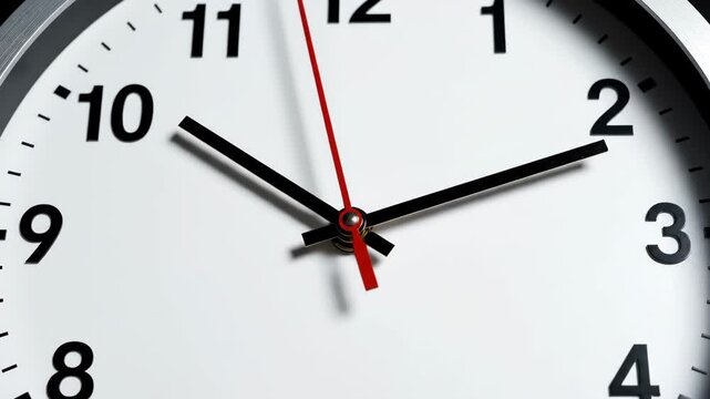 Close-up view of clock showing time at two o'clock with black and red hands on white background. Clock features clear numbers and precise markers making time easy to read.