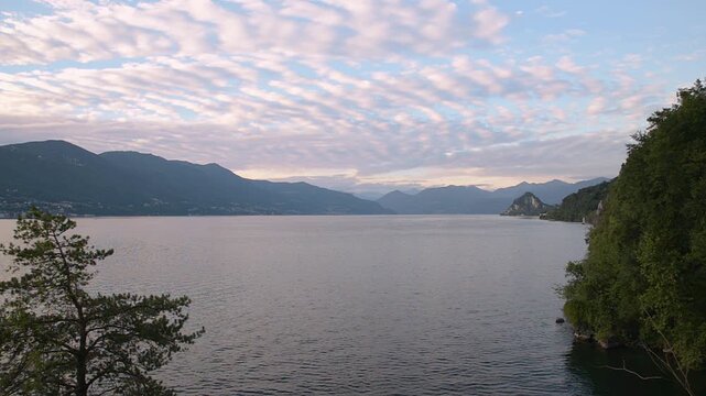 Lake Maggiore at sunset, Italy &ndash; panoramic elevated view with mountains, rippled water and colorful clouds, static tripod shot between Calde and Maccagno area