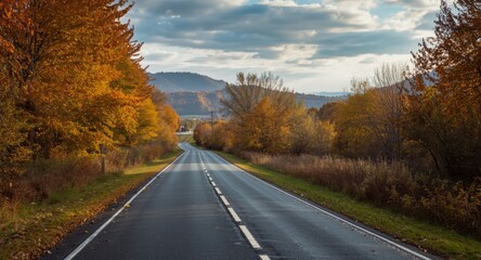 Obraz premium Calm autumn countryside scene with a quiet road surrounded by vibrant fall foliage and peaceful views