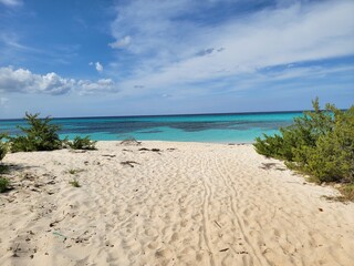 Wide angle view of pristine white sand beach and turquoise Caribbean sea under a cloudy sky in Bahia de las Aguilas