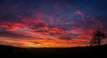 Fototapeta premium Dramatic sunset clouds glowing with vibrant colors in the evening sky over peaceful nature