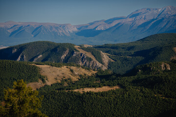 Majestic mountain range with forested valleys and clear blue sky