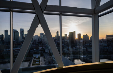 Fototapeta premium A scenic view of a city skyline at sunset, framed by a large window, creating a theatrical effect that emphasizes the contrast between the vibrant sky and the urban environment.