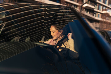 Naklejka premium Woman buckling up seatbelt driving in city