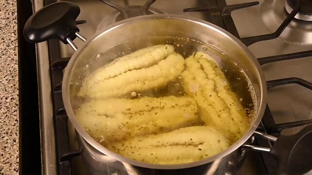 Caigua, a traditional south american vegetable, cooks in boiling seasoned water inside a steel pot