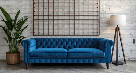 Fototapeta premium Contemporary lounge area with blue quilted sofa, white brick wall and brown grid backdrop, decorated with plant and lamp
