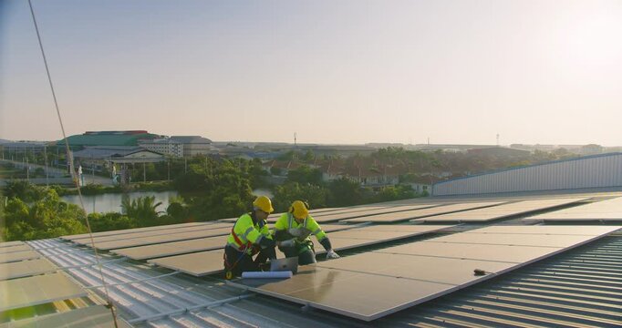 Two professional engineers are inspecting a solar panel system on a factory rooftop, focusing on renewable energy efficiency, quality control, and sustainable technology.