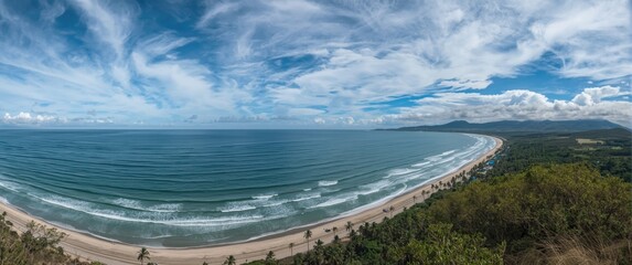 Elevated shot of a serene beach with calm ocean waves and striking cloud patterns above flourishing landscape