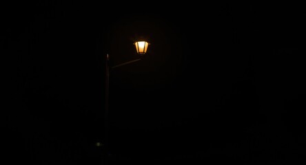 Dimly lit street by a warm glowing streetlight in darkness
