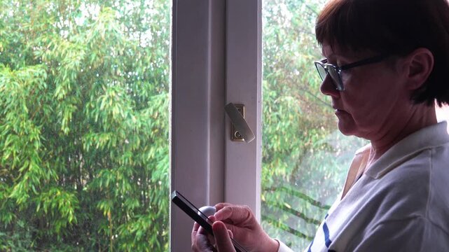 A woman with a smartphone and headphones bobs her head to the beat of the music