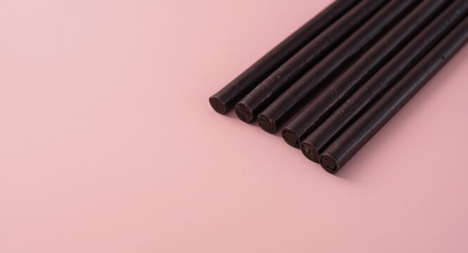 Close up perspective of classic black licorice sticks lying on a faded pastel backdrop including copy space