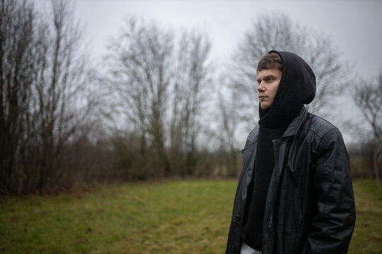 A man in a black leather coat in gloomy weather outdoors in an emotional crisis and sadness