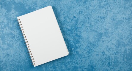 Empty notebook lying on rough blue textured background with copy space