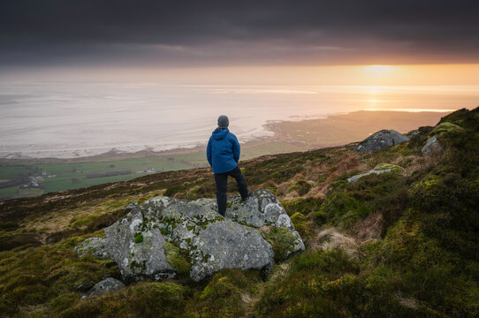 Man on mountain overlooking coastline