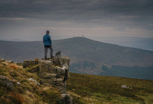 Man and dog on hill top looking towards view