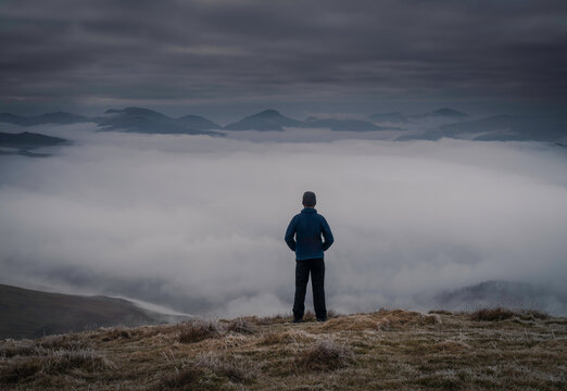 Man on mountain overlooking cloud inversion