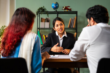 Meeting young couple in modern office discussing on graph, Indian young financial planner
