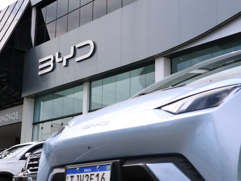 Carro el&eacute;trico em frente &agrave; concession&aacute;ria BYD em Mogi das Cruzes, SP, em 10 de junho de 2026, mostrando fachada moderna, logotipo e tecnologia automotiva.