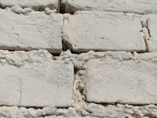 Close-up of a whitewashed relief wall with thick uneven layers of coating on bricks. For minimalist backgrounds, design elements, and tactile textures. © Tapasii