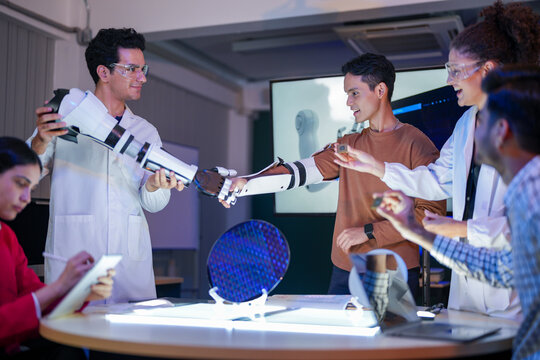 Proud diverse STEM workforce displaying advanced robotic arm and silicon wafer in R&D lab. Leading the future of AI technology and cybernetic hardware innovation.