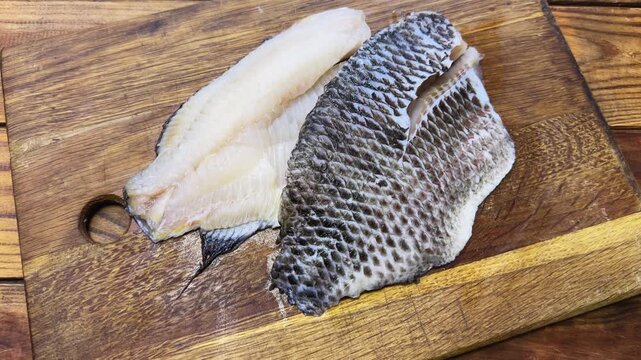 Raw defrosted dourade fillets on cutting board on rustic table