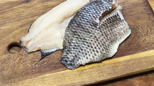 Raw defrosted dourade fillets on cutting board on rustic table