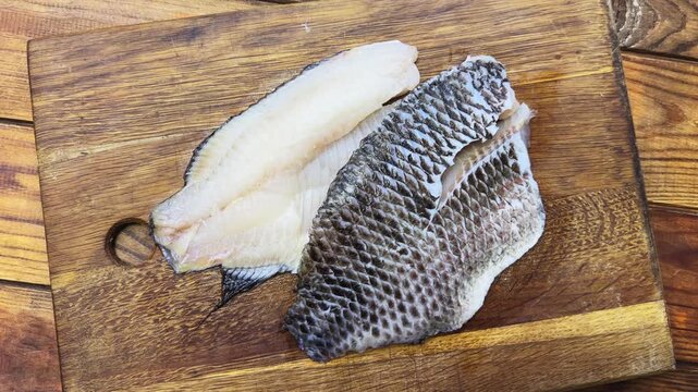 Raw defrosted dourade fillets on cutting board on rustic table
