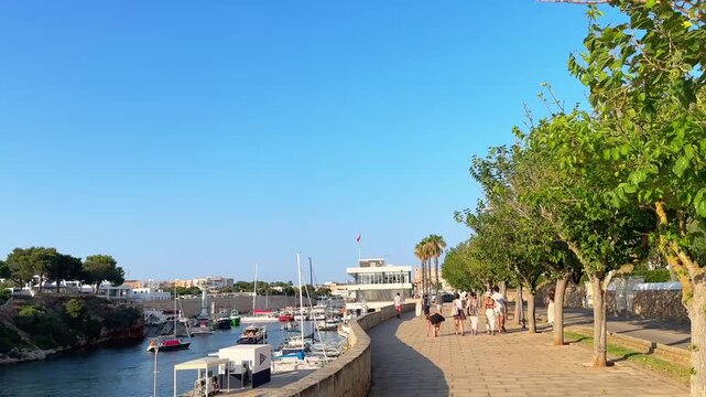 People strolling along Ciutadella harbor promenade in Menorca summer