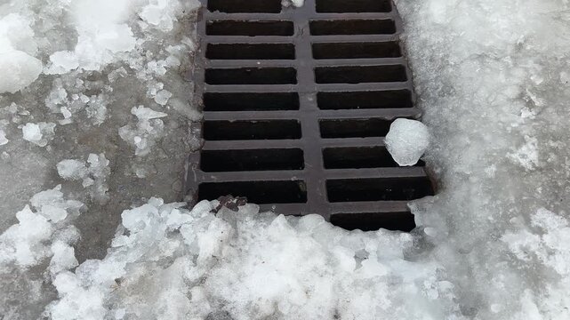 Cast iron drainage grate during snow melting in overcast day