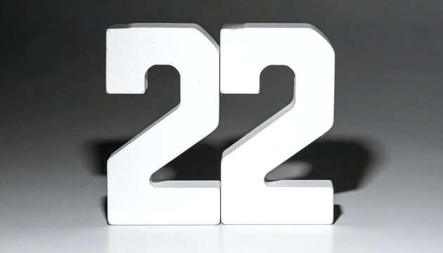 Two large white numerals, '22', stand tall on a reflective surface against a blurred grey background