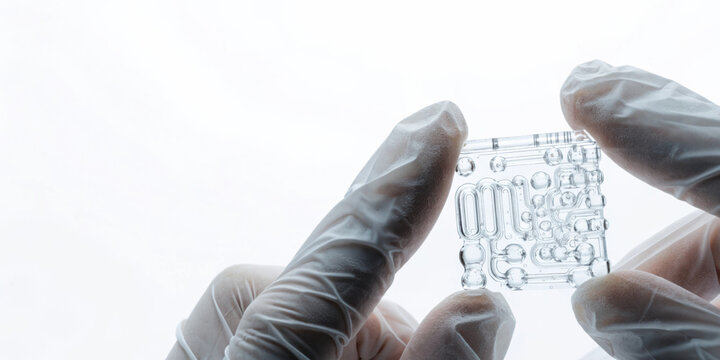 Medical technology microfluidic chip held by gloved hands showcasing precise laboratory device