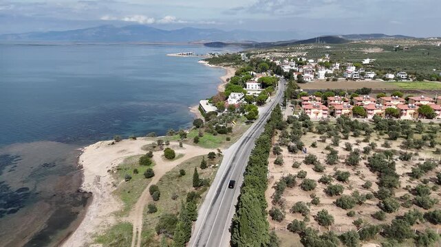 Drone flying along coastal road near Didim Turkey with seaside villas