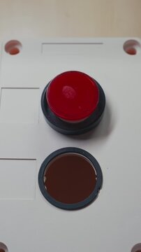 Finger Pushing a Red Button Resembling a Clown&rsquo;s Nose on a White Face