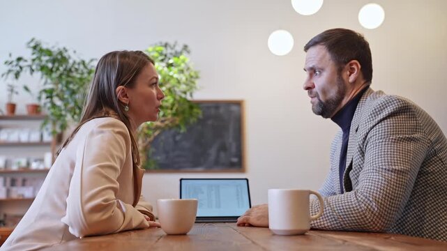 Man and woman working closely at cafe table, drinking coffee and reviewing notes in casual office. Coffee, notes, cafe, teamwork, casual office.