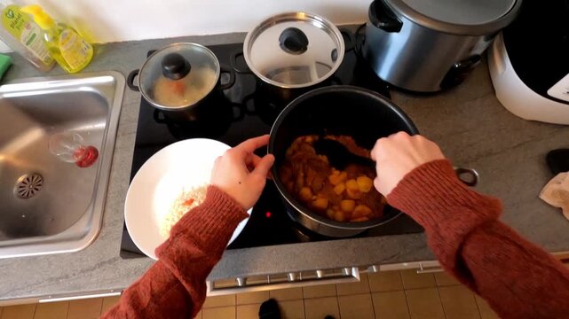 POV of hands serving meat in sauce with potatoes on a plate with rice to eat.