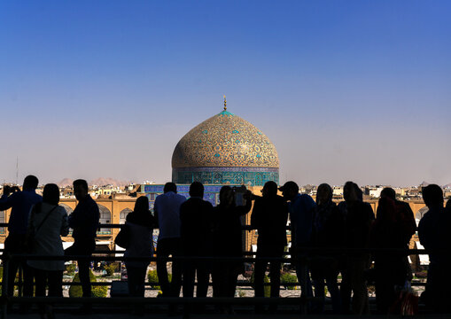 Silhouettes of tourists looking at Sheikh Lutfollah Mosque standing on Naghsh-i Jahan Square, Isfahan Province, Isfahan, Iran