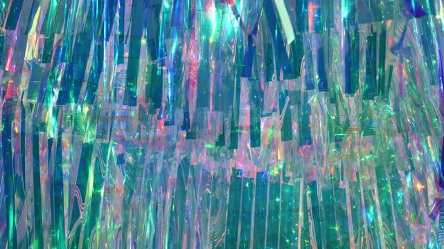 Iridescent tinsel streamers creating a sparkling holographic rainbow background texture